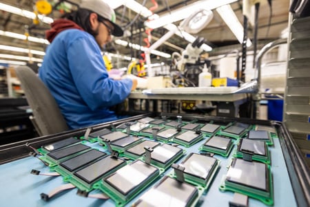 A production staff member at RIS works diligently using specialized tools and equipment to produce high-quality assemblies.