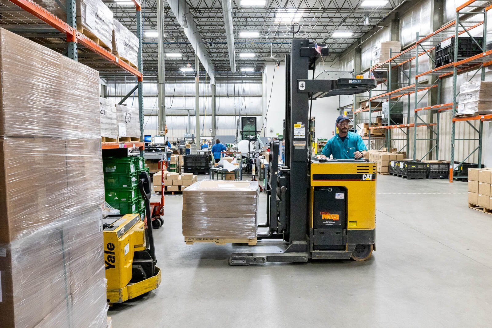 A production worker at RIS uses a skid loader to transport wrapped pallets, ready for shipping out to customers, around an RIS warehouse.