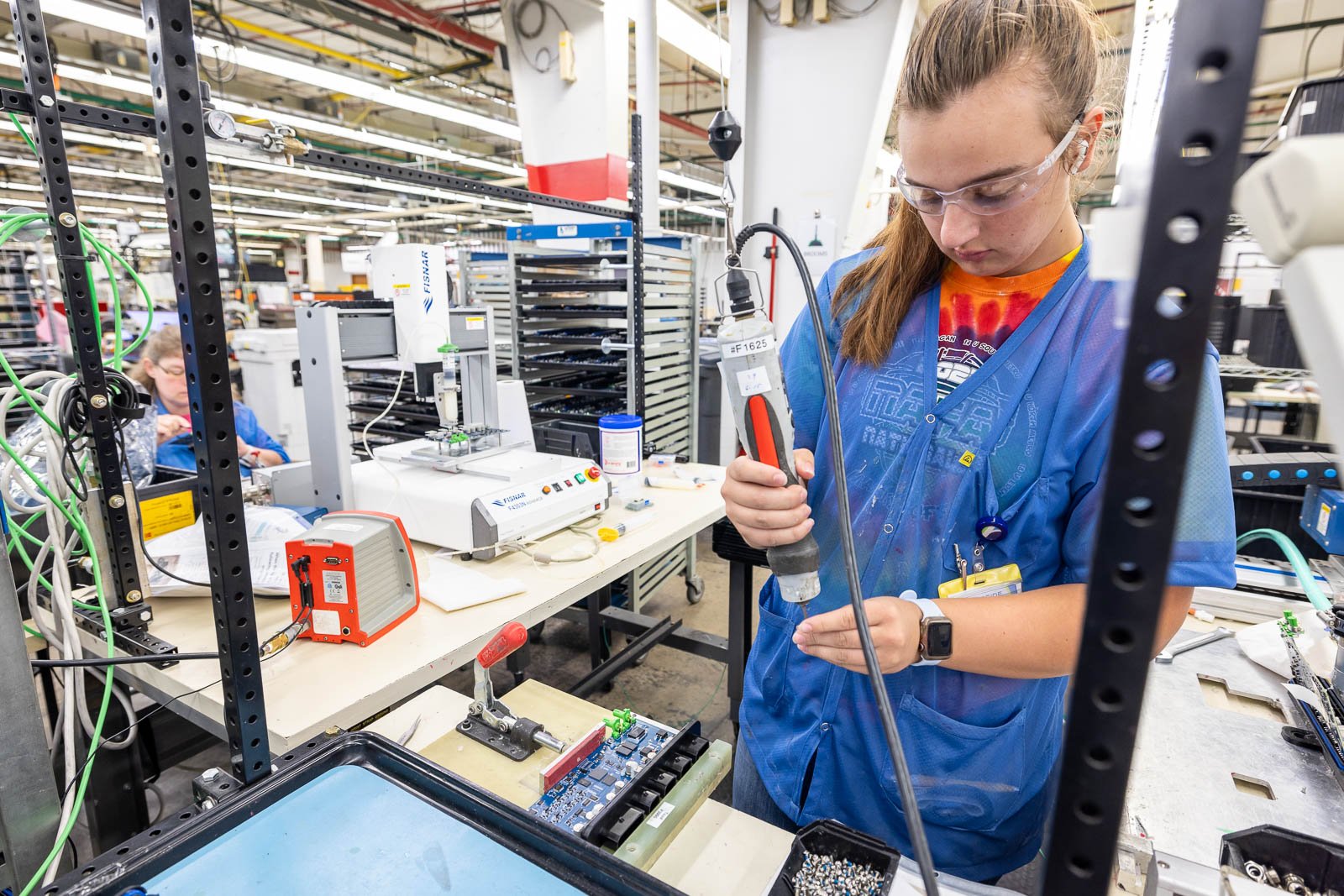 A production worker at RIS works on an assembly using powered tools designed to reduce strain and increase quality control.