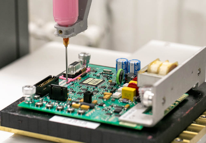 Close up of  a cobot adding protective material to a PCBA.