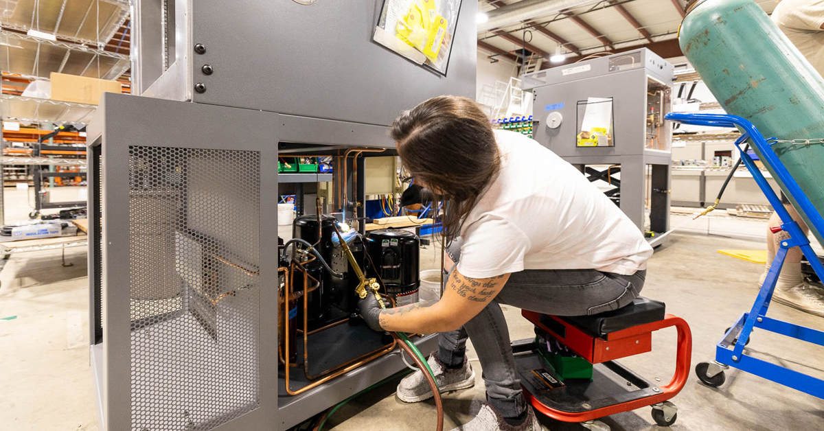 Production worker brazing on a large enclosure box build.
