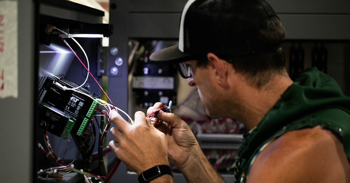 RIS worker assembles complex wire harnessing inside a large box build.