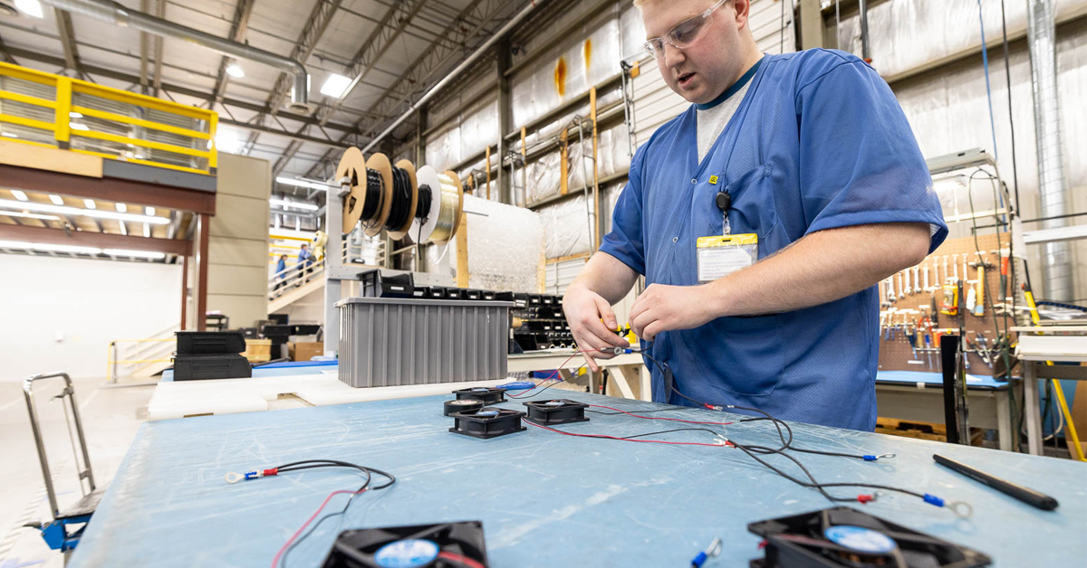 RIS worker completing wire assemblies attached to mechanical components.