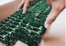 Close up of a hand placing identical PCBAs into a box as part of a reverse logistics cycle.